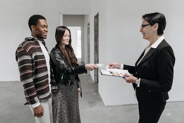 a-couple-handing-over-a-document-to-a-business-professional-holding-a-clipboard